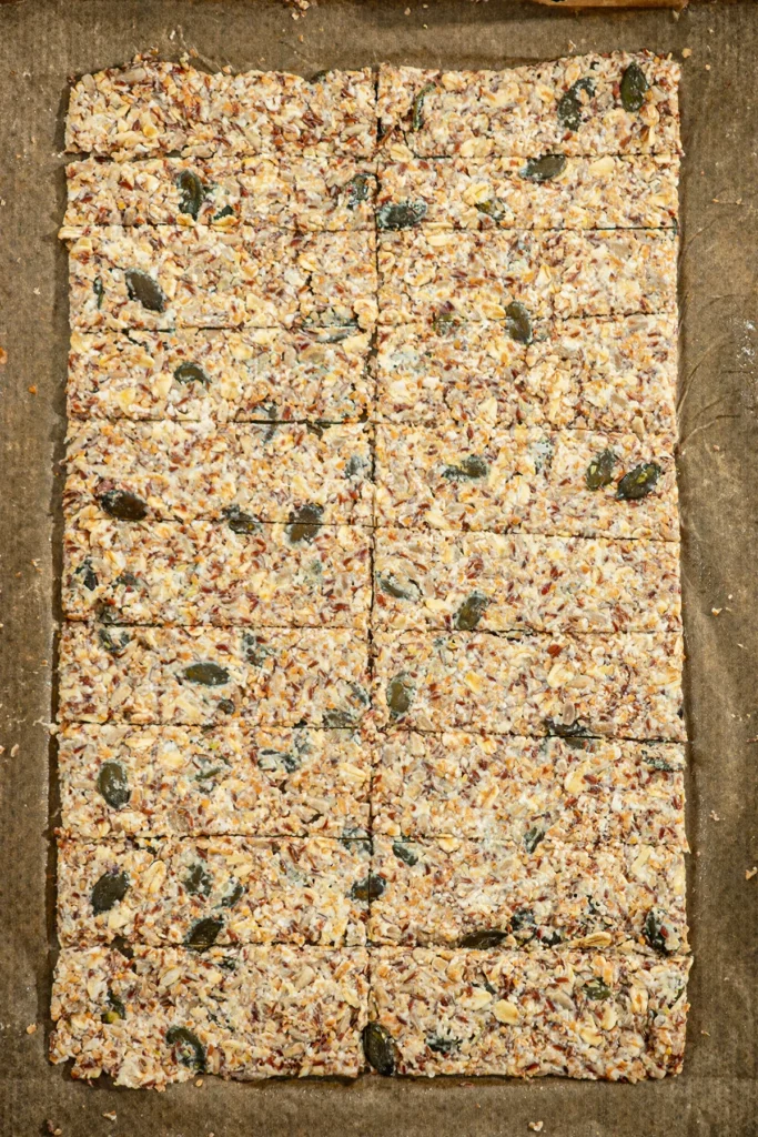 View of a baking tray with rolled out crispbread with seeds before baking.