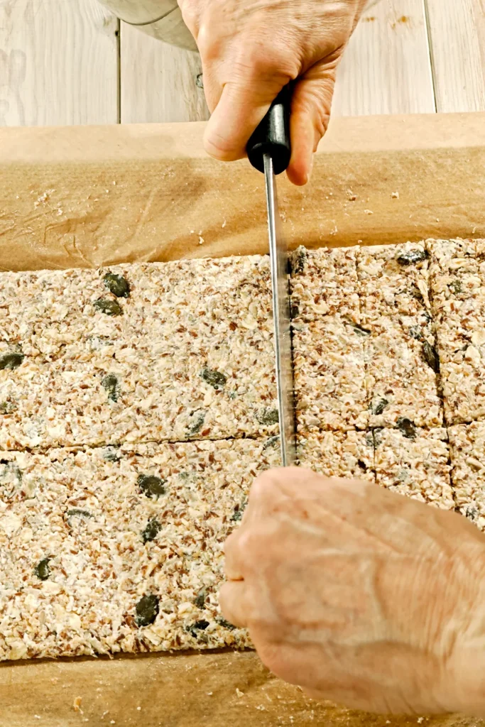 A large knife presses dividing lines into the crispbread dough.