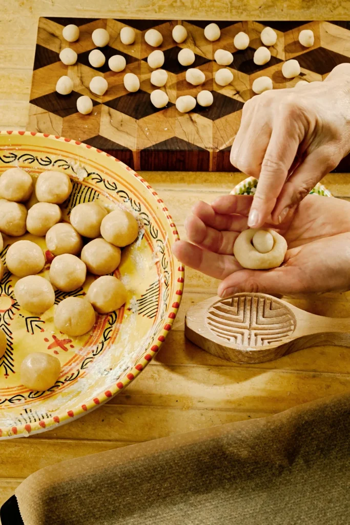 Hands filled the hollow in the cookie dough with a marzipan ball.