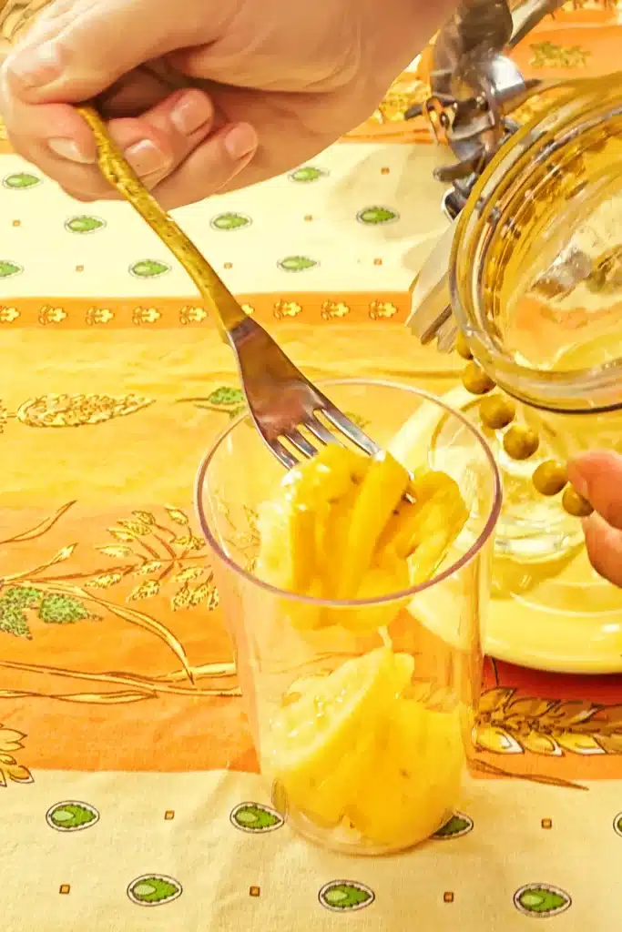 The salted lemons are placed in a narrow container with the juice brine.