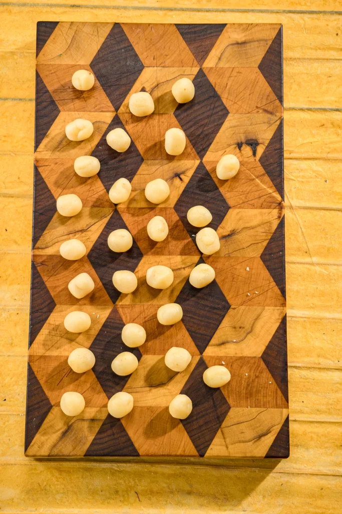 The rolled marzipan balls lie on a wooden board.