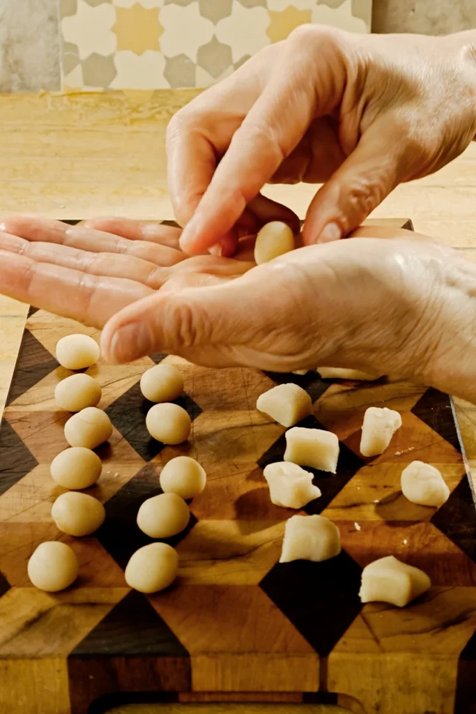 Hands roll the marzipan balls from the portioned baking marzipan pieces.