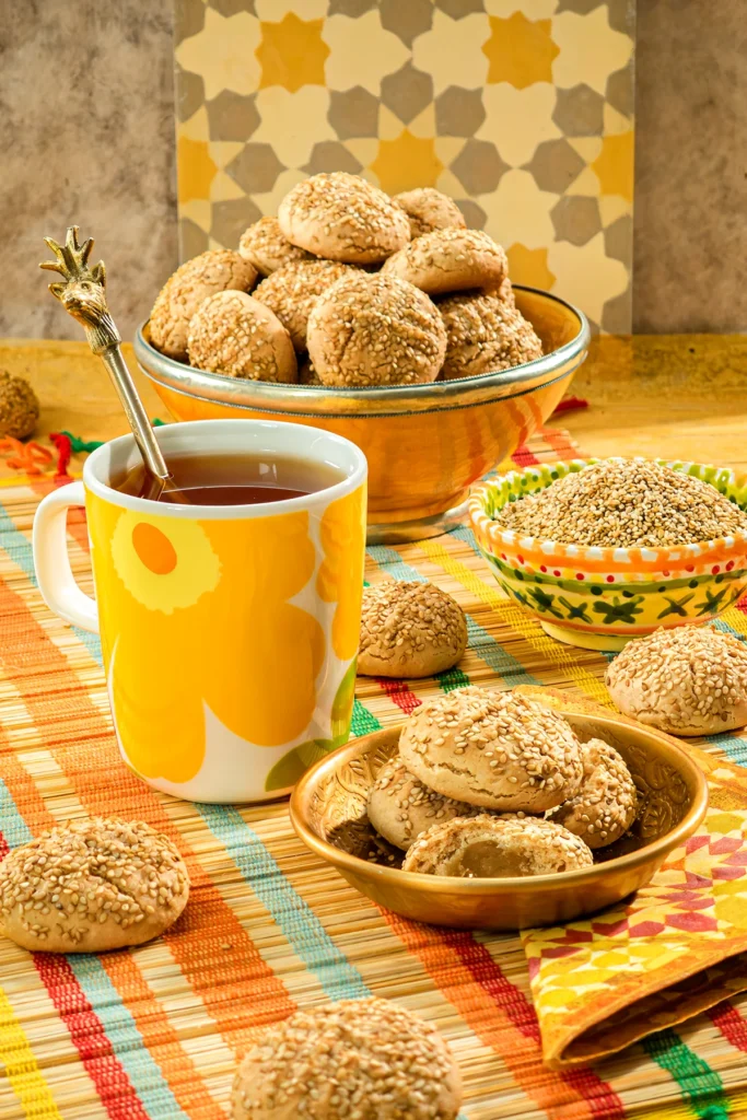 The sesame cookies are served in bowls with a cup of tea.