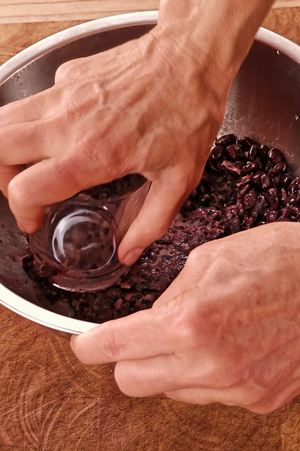 The black beans are crushed with a glass.