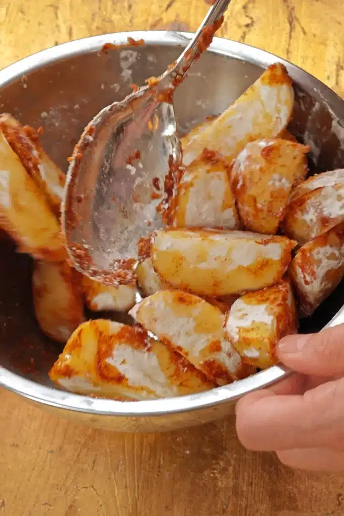 The potato wedges are moved so that the spices are evenly distributed.